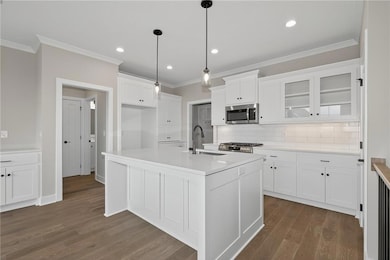 Kitchen with crown molding, backsplash, white cabinets, glass insert cabinets, and dark wood-style flooring