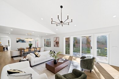 Living room featuring light wood-style floors, a chandelier, recessed lighting, high vaulted ceiling, and arched walkways