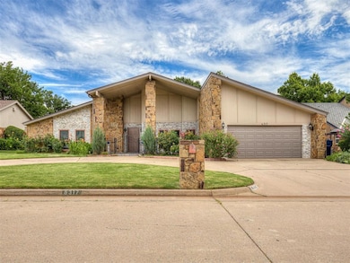 Mid-century modern home featuring stone siding, driveway, a front yard, and a garage
