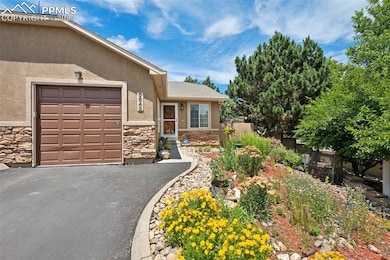 View of front of property with stone siding, stucco siding, an attached garage, and driveway