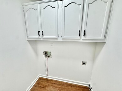 Laundry room featuring dark wood-type flooring, hookup for a washing machine, cabinet space, and hookup for an electric dryer