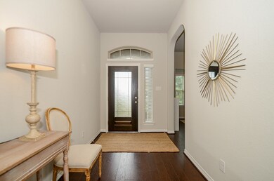 A formal entryway is accented by a gorgeous glass-paneled wooden door. A side window and transom window provide natural light. The opening to the left of the door as you walk in leads to the study.