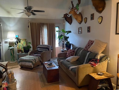 Living area with a ceiling fan and wood finished f