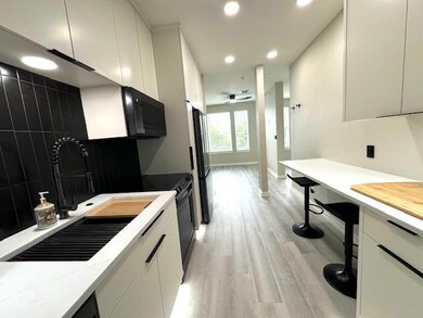 Kitchen with a sink, black appliances, light wood