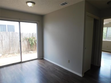 Unfurnished room featuring dark wood-style flooring and a textured ceiling