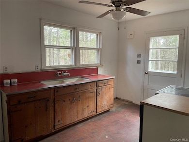 Kitchen with brick patterned flooring, light countertops, ceiling fan, and brown cabinets