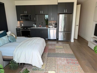 Bedroom featuring fridge, a sink, wood finished f