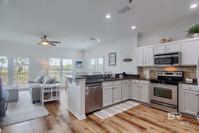 Kitchen featuring stainless steel appliances, open floor plan, a peninsula, ornamental molding, and decorative backsplash