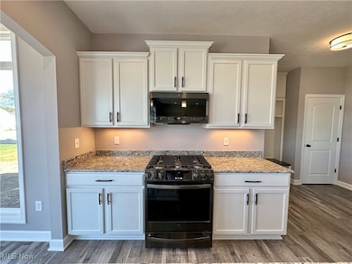 Kitchen featuring range with gas stovetop, wood-type flooring, and white cabinetry