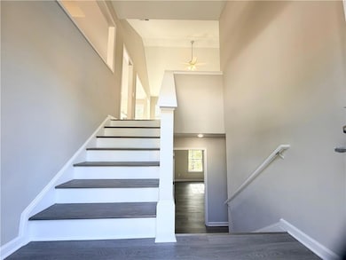 Stairway with wood finished floors, a high ceiling, and a ceiling fan