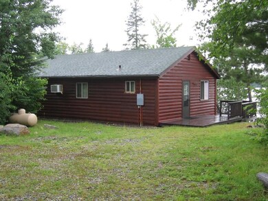 View of home's exterior featuring faux log siding, a deck, a shingled roof, and a lawn