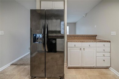 Kitchen with white cabinetry and black fridge with