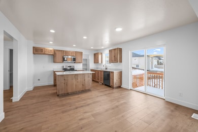 Kitchen with recessed lighting, light wood-style flooring, a center island, stainless steel appliances, and brown cabinetry