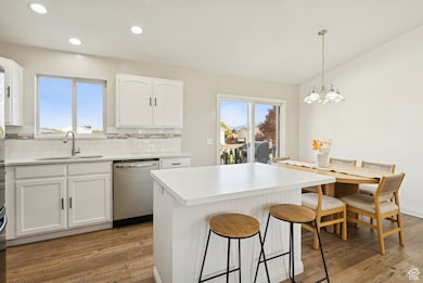 Kitchen with white cabinets, tasteful backsplash, a center island, light wood-type flooring, and dishwasher