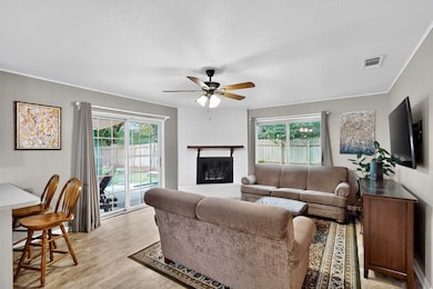 Living area featuring a brick fireplace, ceiling fan, a textured ceiling, and ornamental molding