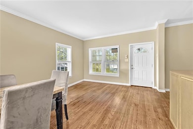 Entryway featuring wood finished floors, crown molding, and baseboards
