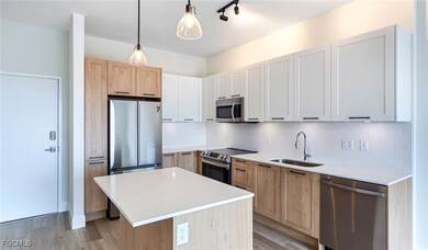 Kitchen with tasteful backsplash, light wood-type flooring, appliances with stainless steel finishes, a sink, and light countertops