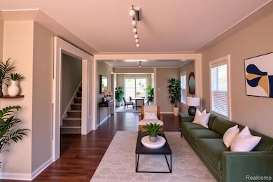 Living room featuring dark wood-style flooring, stairs, and rail lighting