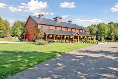 View of front of home featuring a metal roof, covered porch, a standing seam roof, a front lawn, and driveway