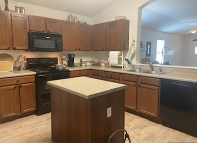 Kitchen with black appliances, light wood finishe