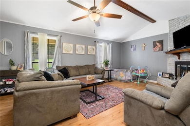 Living area featuring a ceiling fan, a fireplace, and wood finished floors