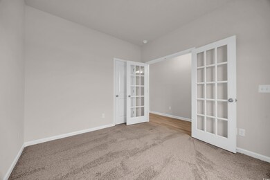 Carpeted empty room featuring french doors and bas