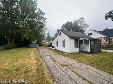 View of home's exterior with a lawn, a storage unit, a sunroom, and driveway