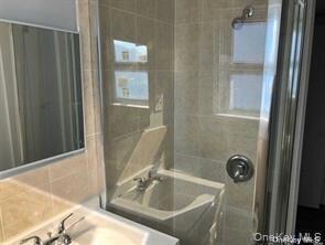 Bathroom with tile walls, a shower, vanity, and a tub to relax in