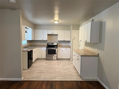 Kitchen featuring electric stove, wood finish floors, white cabinetry, and dishwasher