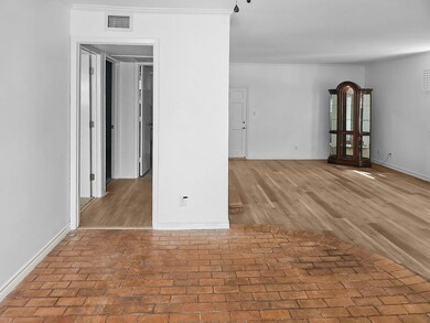 Empty room with brick floor, visible vents, basebo
