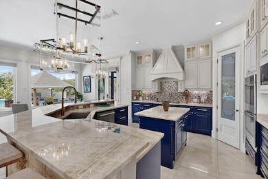 Kitchen with a kitchen breakfast bar, blue cabinetry, pendant lighting, light stone counters, and crown molding
