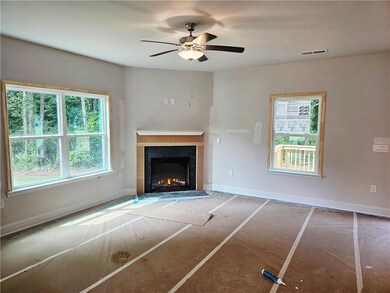 Unfurnished living room featuring a fireplace with flush hearth, ceiling fan, and baseboards