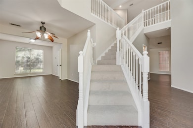 Stairs with wood finished floors, a ceiling fan, and a towering ceiling