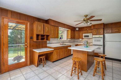 The Kitchen has plenty of counter space and a center island w/breakfast bar that opens to the Dining Area featuring a skylight & door to the covered patio and beautifully planted yard.
