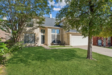 View of front facade with concrete driveway, a shingled roof, brick siding, a front yard, and a chimney