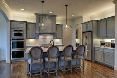 Kitchen with arched walkways, gray cabinetry, stai