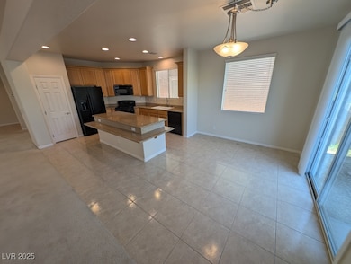 Kitchen featuring recessed lighting, black appliances, a kitchen island, decorative light fixtures, and light tile patterned flooring