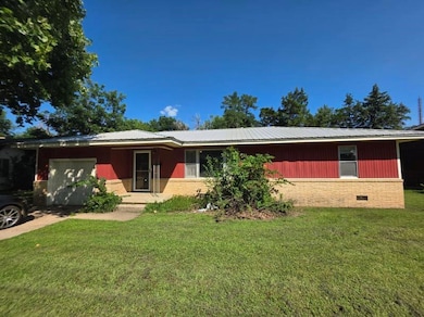 Single story home with an attached garage, a front lawn, crawl space, and a metal roof