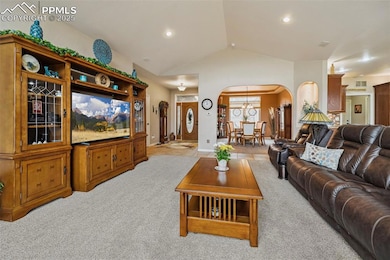 Living area featuring light carpet, arched walkways, recessed lighting, and lofted ceiling