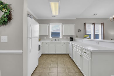 Kitchen with white appliances, light tile patterned flooring, a peninsula, and healthy amount of natural light