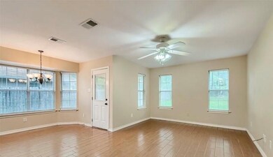 Empty room featuring hardwood / wood-style flooring and ceiling fan with notable chandelier