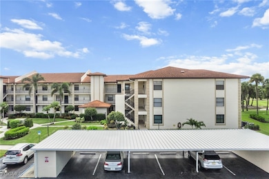 View of apartment building / complex with covered and uncovered parking