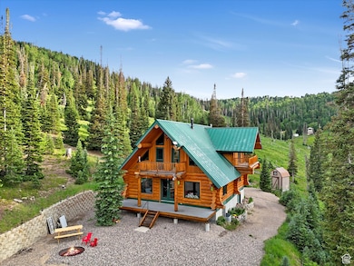 Back of property featuring log exterior, a view of trees, a metal roof, a standing seam roof, and a shed