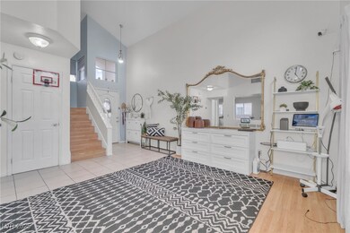 Entrance foyer with high vaulted ceiling, light wood-style flooring, and stairway