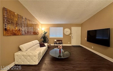 Living area with a textured ceiling and dark wood-type flooring