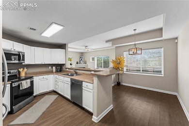 Kitchen with appliances with stainless steel finishes, white cabinets, a sink, visible vents, and a peninsula