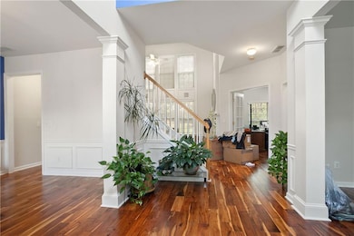 Entryway with ornate columns, stairway, hardwood / wood-style floors, and a wainscoted wall. To the right you have an office area or sitting room and to the left you have a formal dining room