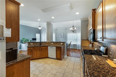 Kitchen featuring stainless steel appliances, brown cabinets, backsplash, a ceiling fan, and light tile patterned flooring