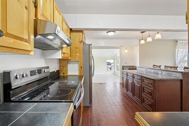 Kitchen with stainless steel appliances, under cabinet range hood, pendant lighting, plenty of natural light, and dark wood-type flooring