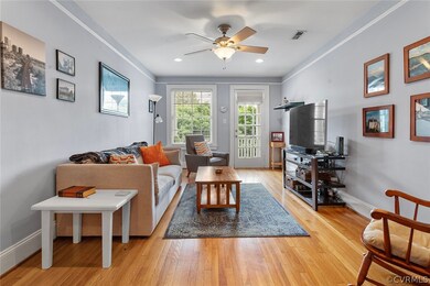 Living room with crown molding, ceiling fan, and l